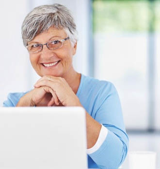 Femme résidente en EHPA ou résidence senior portant des lunettes de vue face à un ordinateur